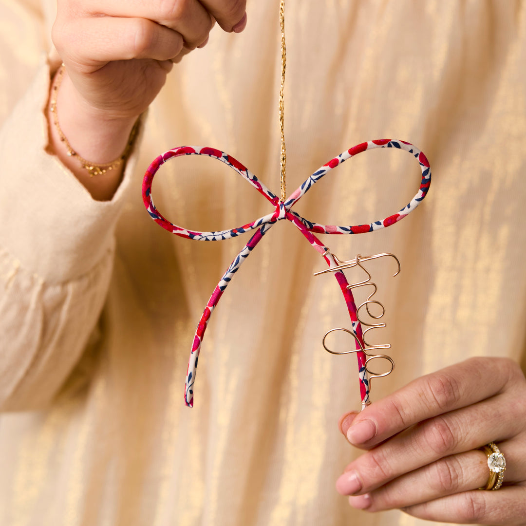 Liberty London Wiltshire bow ornament personalised with name 'freya' held by a person 