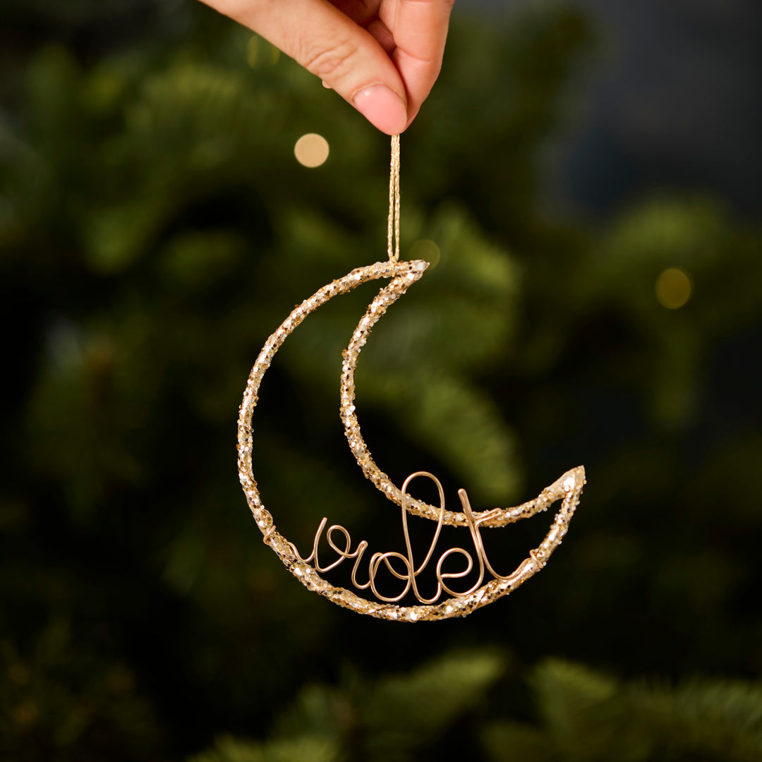 Decorative gold crescent moon Christmas ornament personalised with 'Violet' on a Christmas tree
