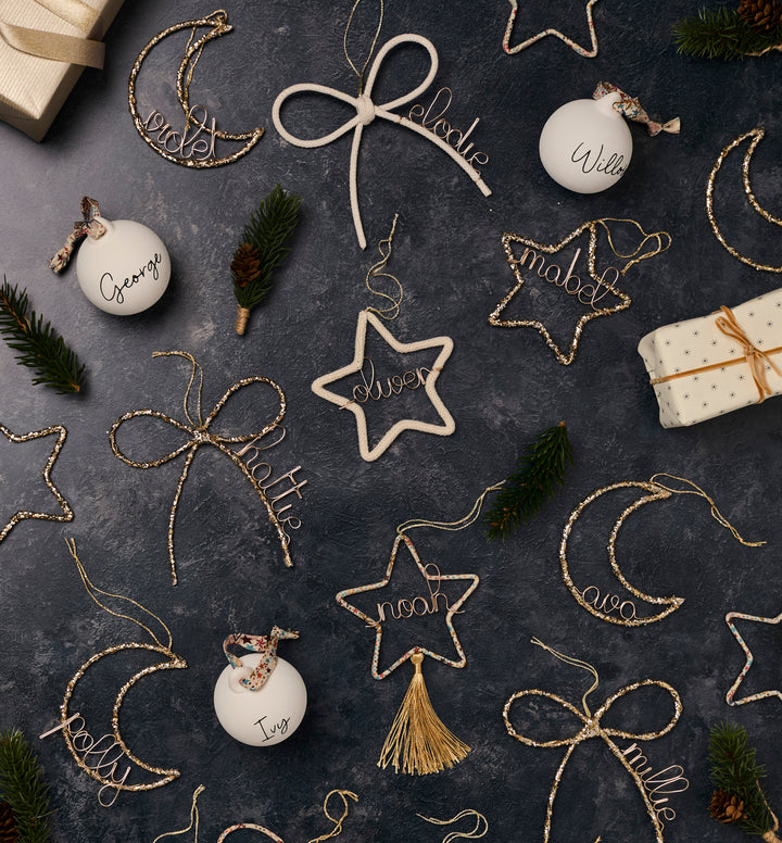 gold and white Christmas ornaments on a dark surface with gift boxes.