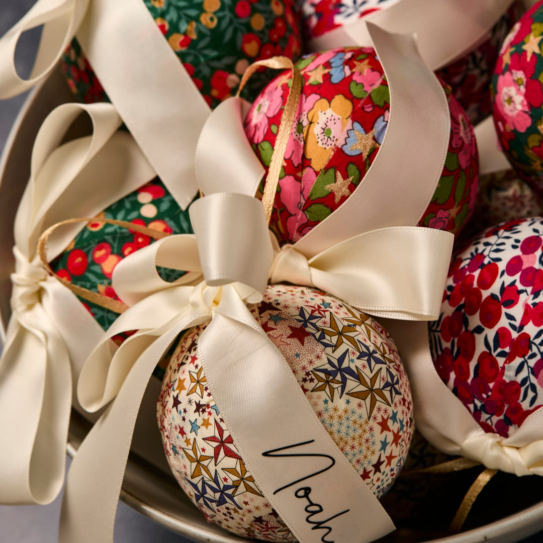 Close up of Liberty London floral fabric baubles with personalised ribbons 